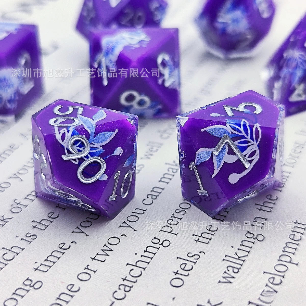 A set of purple resin dice featuring a black kitten design on the faces, displayed on white paper.