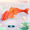 An orange swimming shark toy is shown swimming in water surrounded by pink flowers and green leaves.