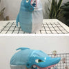 A light blue shark-shaped toy with a mouth and teeth is displayed on a black grid surface.