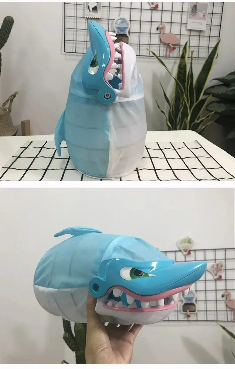 A light blue shark-shaped toy with a mouth and teeth is displayed on a black grid surface.