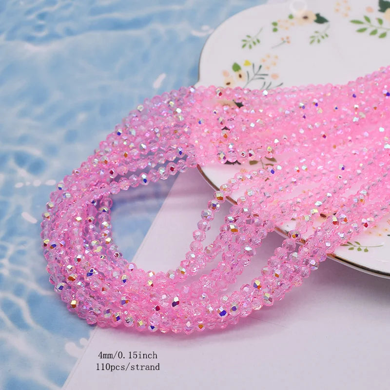 Pink faceted crystal rondelle beads for jewelry making displayed on a white surface.