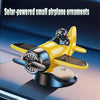 A yellow solar-powered rotating airplane ornament resting on a dark dashboard surface.