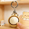 A white, round fidget toy is placed inside a wooden keychain container with a silver clasp.