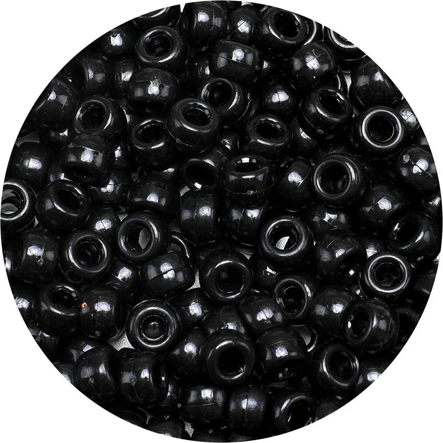 A close-up view of small, black pony beads scattered across a dark surface.