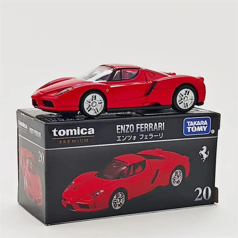 A red Enzo Ferrari Tomica die-cast sports car model displayed in its packaging.