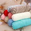 A collection of three skeins of soft cotton blend yarn in various shades including gray, red, pink, beige, and turquoise.