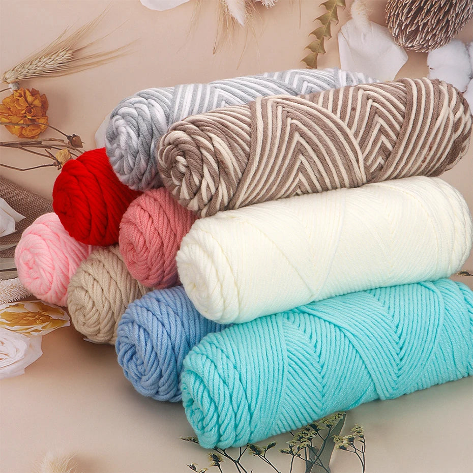 A collection of three skeins of soft cotton blend yarn in various shades including gray, red, pink, beige, and turquoise.