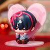 A mini figure collectible of a character with dark blue hair and pink accents, displayed against a heart-shaped background.
