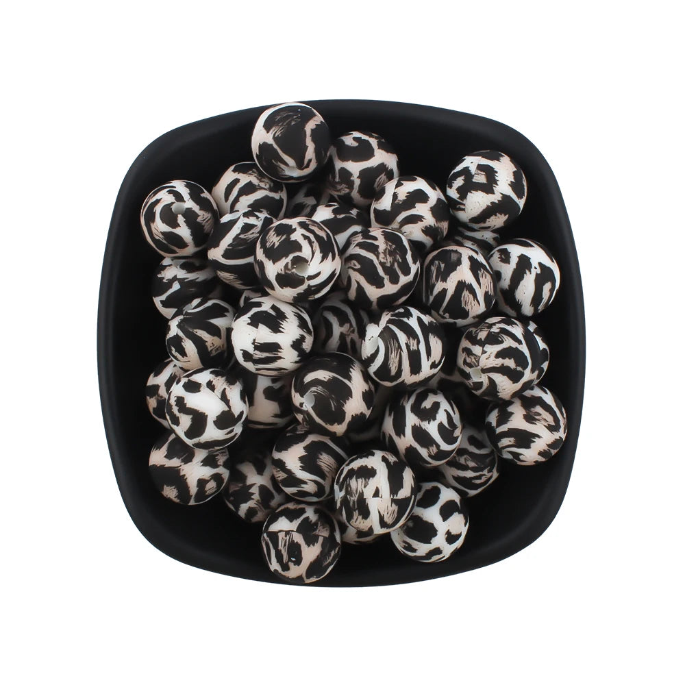 A bowl filled with small black and white leopard print silicone beads for jewelry making.