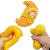 An orange squishy croissant stress relief toy is shown next to a yellow ball.