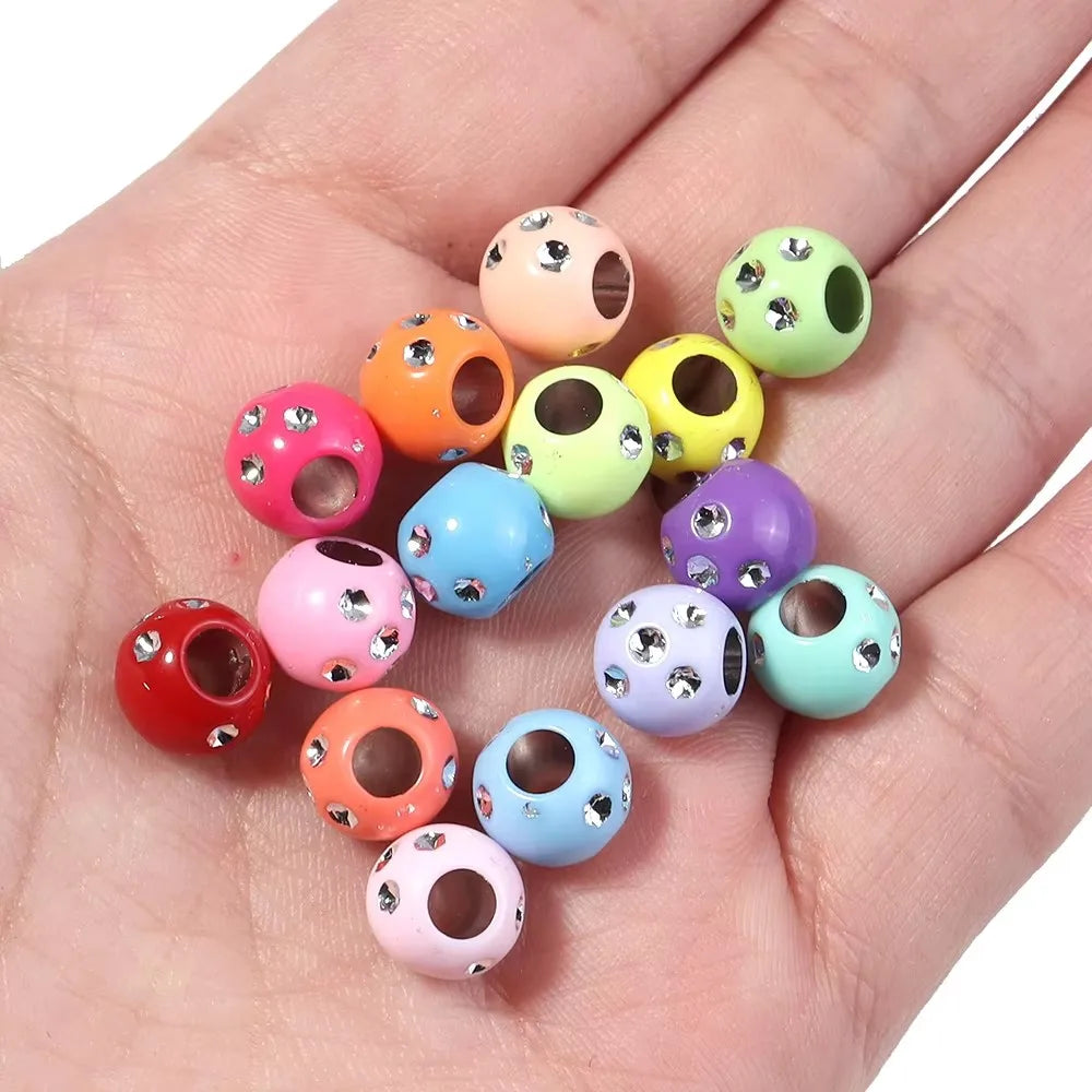 A collection of colorful rhinestone acrylic spacer beads in various shades of pink, green, yellow, and purple are displayed o