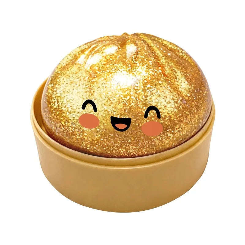 Un jouet anti-stress en forme de dumpling doré et pailleté, posé dans un plat jaune clair.