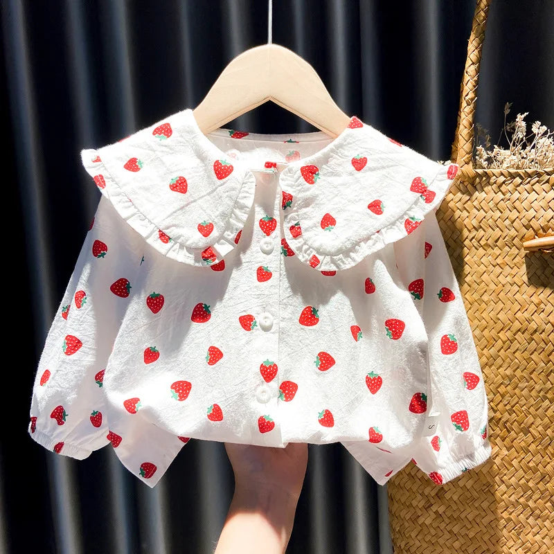 White baby girl long-sleeve shirt with a strawberry print, displayed on a wooden hanger.