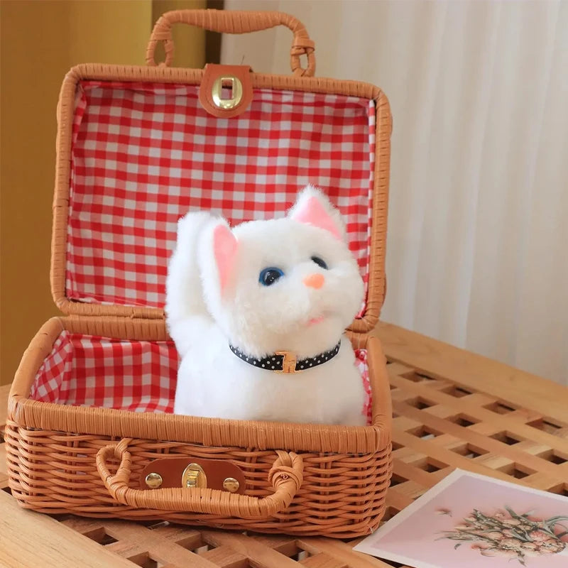 A white plush cat toy with pink ears and a black collar is displayed inside a woven wicker box.