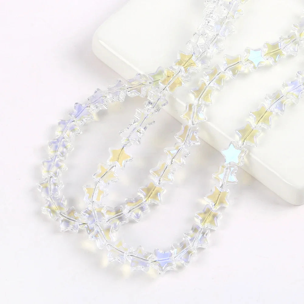 Clear glass star spacer beads arranged in two strands on a white surface for jewelry making
