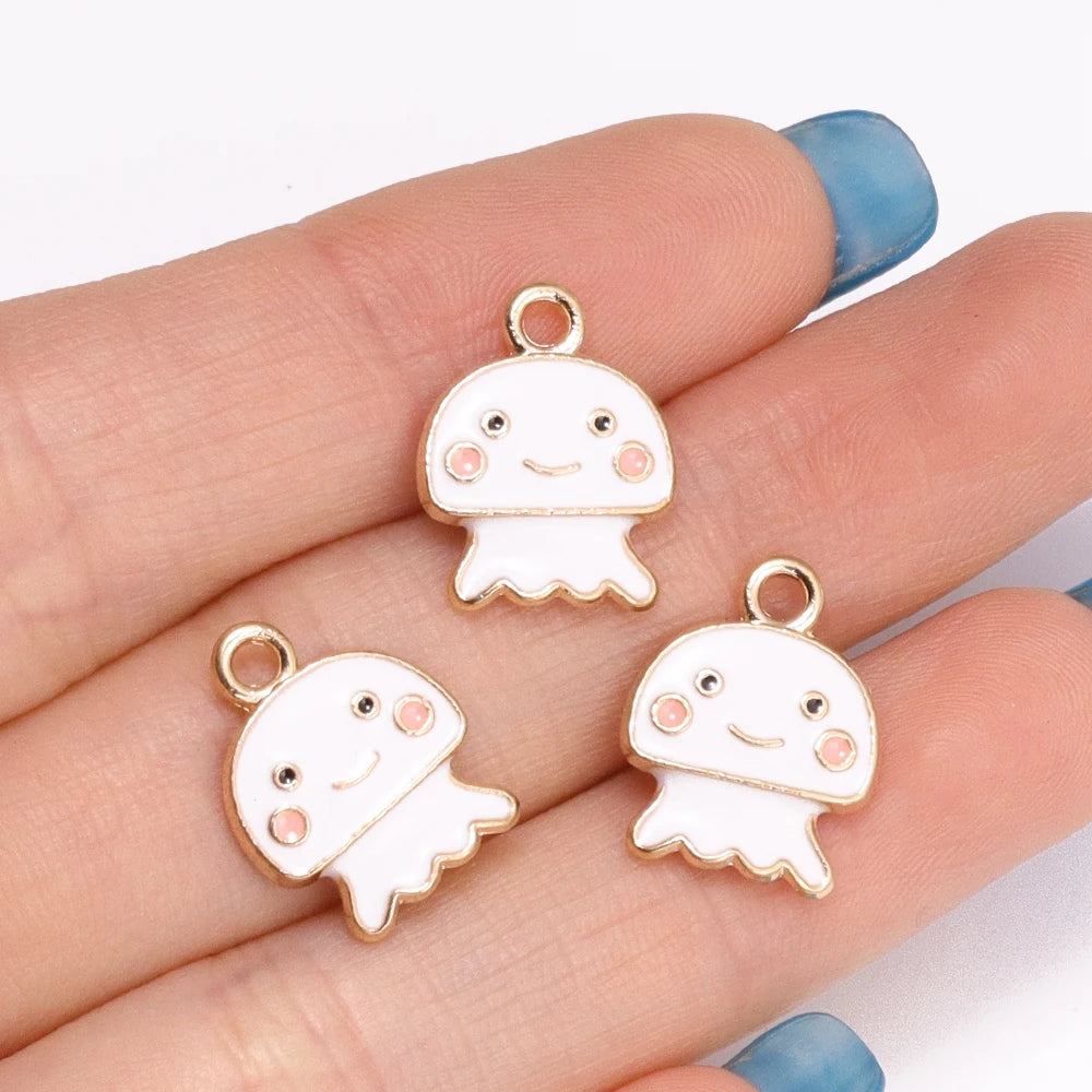 Two white enamel marine life charms with pink accents are displayed on a hand.