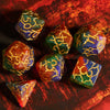 A set of seven frosted crack resin polyhedral dice in various shades of green, gold, and amber resting on a dark surface.