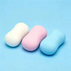 Three squishy fidget blocks in white, pink, and light blue resting on a light blue surface.