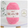 A ball of bright pink chenille yarn labeled for knitting and crochet is displayed on a white surface.