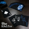 A stack of blue playing cards and a single black card are displayed on a wooden surface.