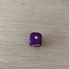 A single purple acrylic die with a white pips on a light wooden surface.