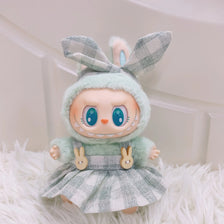 A cute plush doll wearing a green hood and plaid dress with bunny ears.