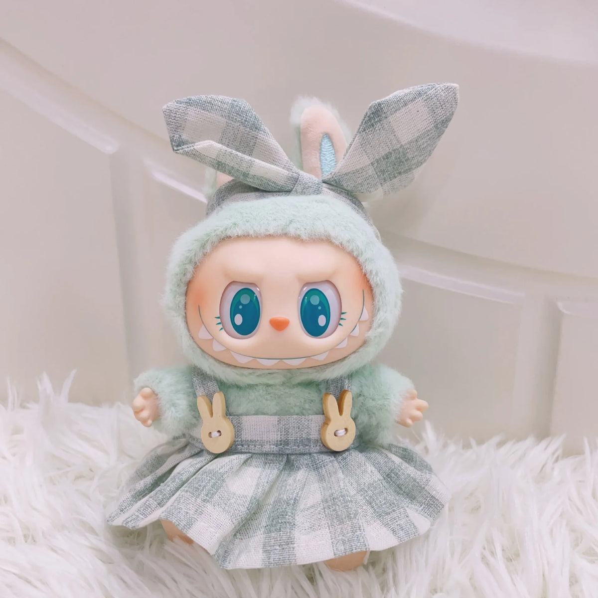 A cute plush doll wearing a green hood and plaid dress with bunny ears.