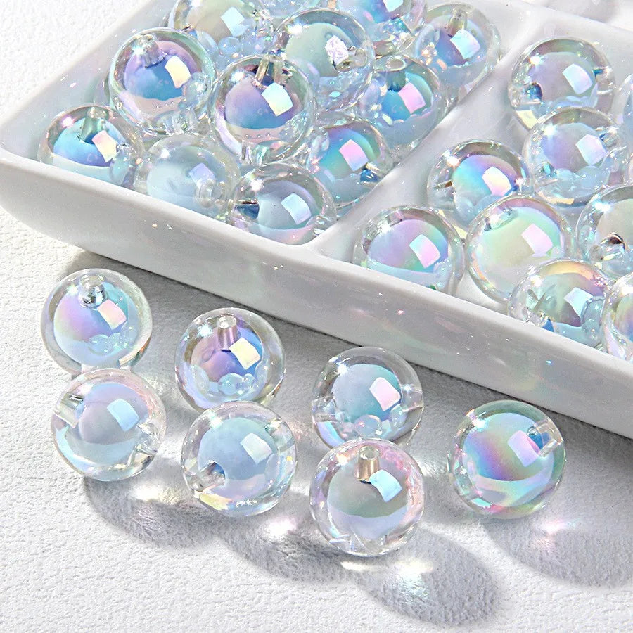 A white dish filled with clear and iridescent acrylic craft beads for jewelry making