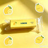 A yellow lemon-shaped squishy fidget toy in a clear plastic bag is shown on a yellow background.