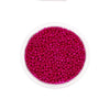 A clear container filled with bright pink glass seed beads for jewelry making