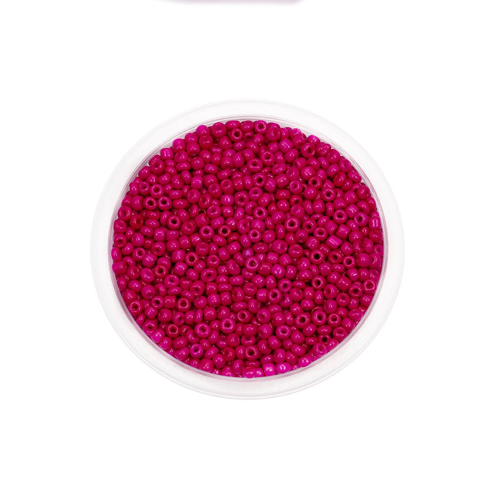 A clear container filled with bright pink glass seed beads for jewelry making