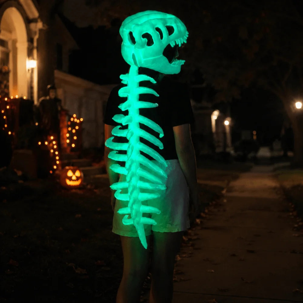 A person wearing a glow-in-the-dark dinosaur skeleton mask with sound effects standing outdoors at night.