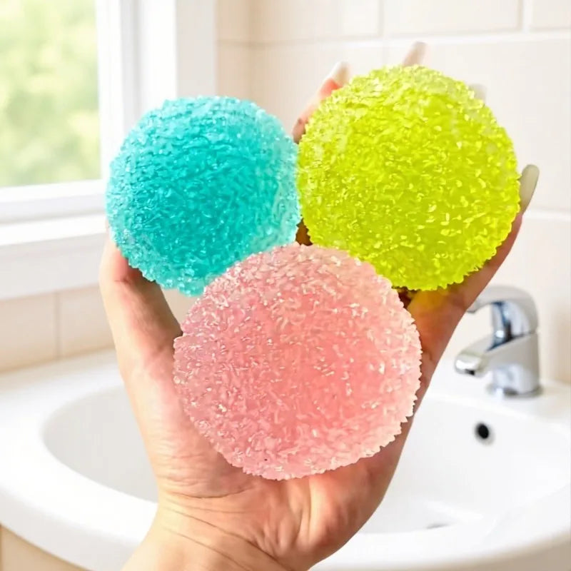 A hand holds three brightly colored squishy ice ball fidget toys: blue, yellow, and pink.