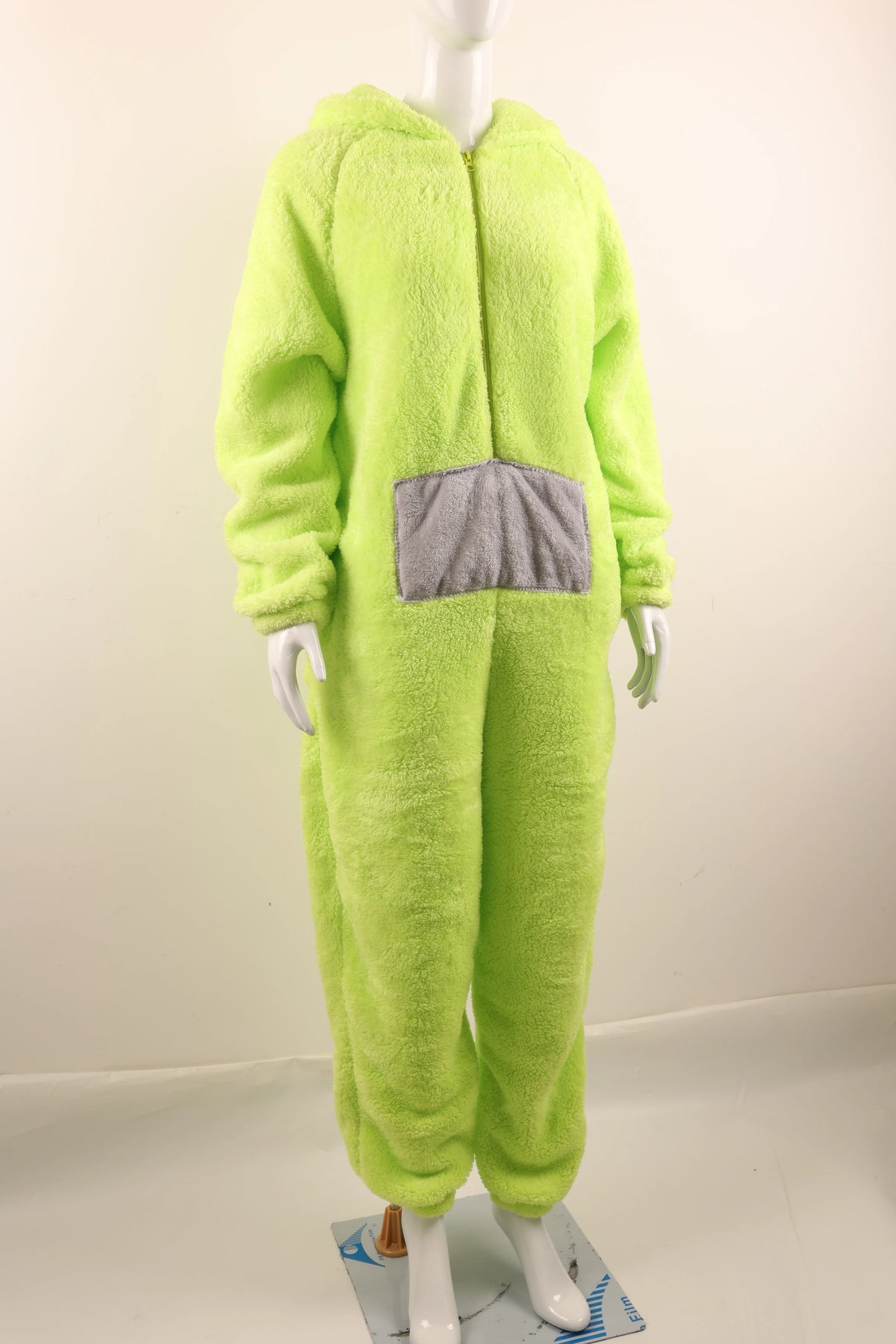 A person wearing a lime green fuzzy one-piece pajama costume with a gray chest patch.