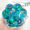 A hand holds a translucent blue iridescent cat paw squishy fidget toy made of resin and crystals.
