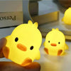 A hand holds a glowing yellow cartoon duck night light, illuminating a surface.