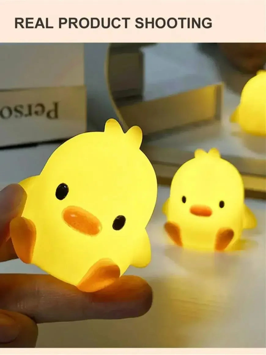 A hand holds a glowing yellow cartoon duck night light, illuminating a surface.