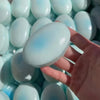 A hand holds a light blue squishy cheese cake stress relief toy surrounded by similar items.