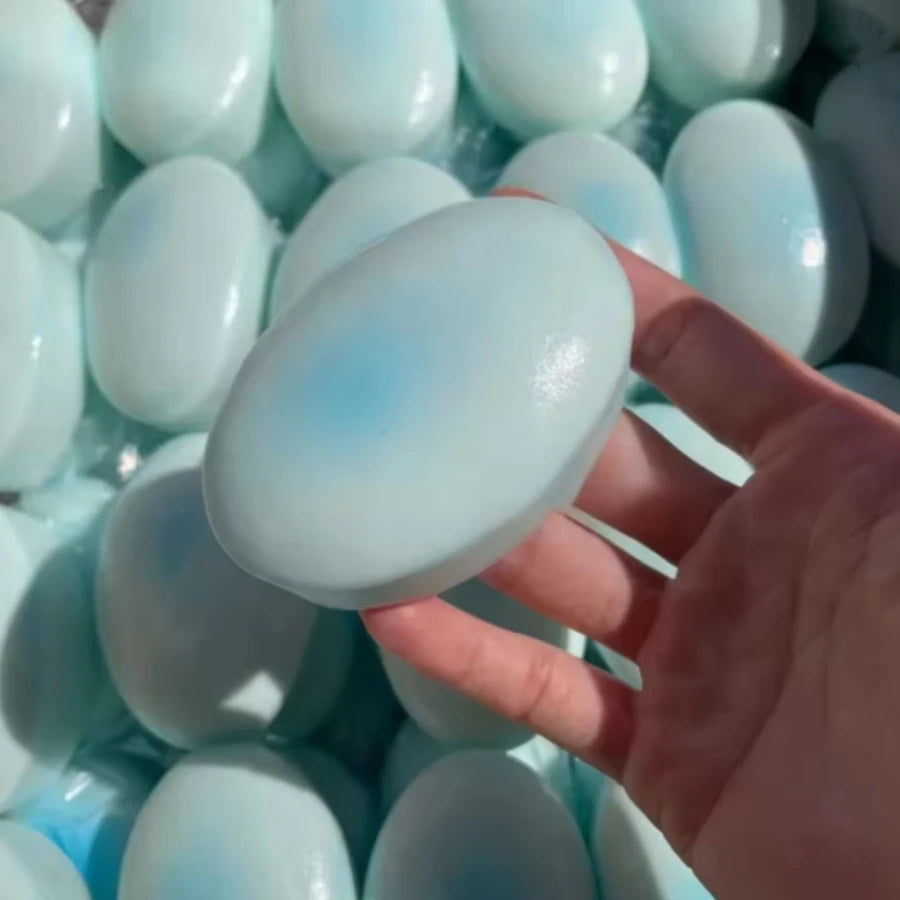 A hand holds a light blue squishy cheese cake stress relief toy surrounded by similar items.