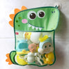 A green storage bag shaped like a frog with a suction cup, holding various small yellow and white toys.