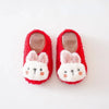 Pair of red fuzzy plush baby slippers with white bunny ears and anti-slip soles