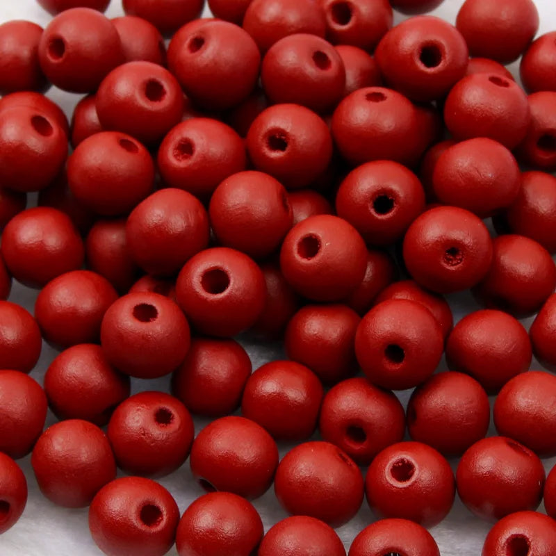 A close-up view of small, round, reddish-brown wooden beads for jewelry making and crafts.
