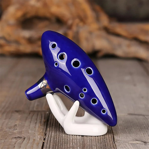 Handgefertigte Keramik-Ocarina in tiefem Blau mit weißen Akzenten, auf einer Holzoberfläche.