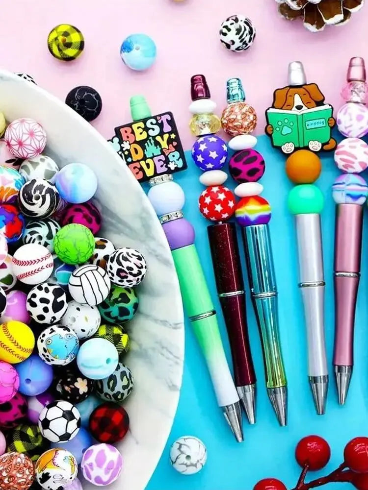 A collection of colorful silicone beads and a pen are displayed on a white dish against a pink background.