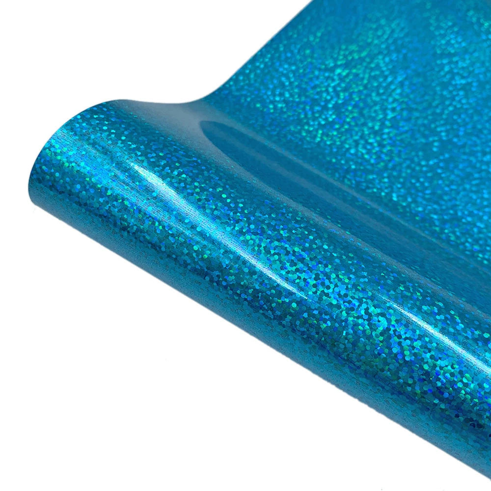 Close-up of a glossy, iridescent blue glitter heat transfer vinyl sheet rolled into a cylinder.