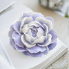 A light purple and white reusable flower silicone mold resting on a white book.