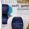 A ball of YEDAN MERINO soft gold wool thread is shown on a white surface.
