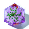 A faceted purple resin D20 die with a liquid swirl design featuring green foliage and gold accents.