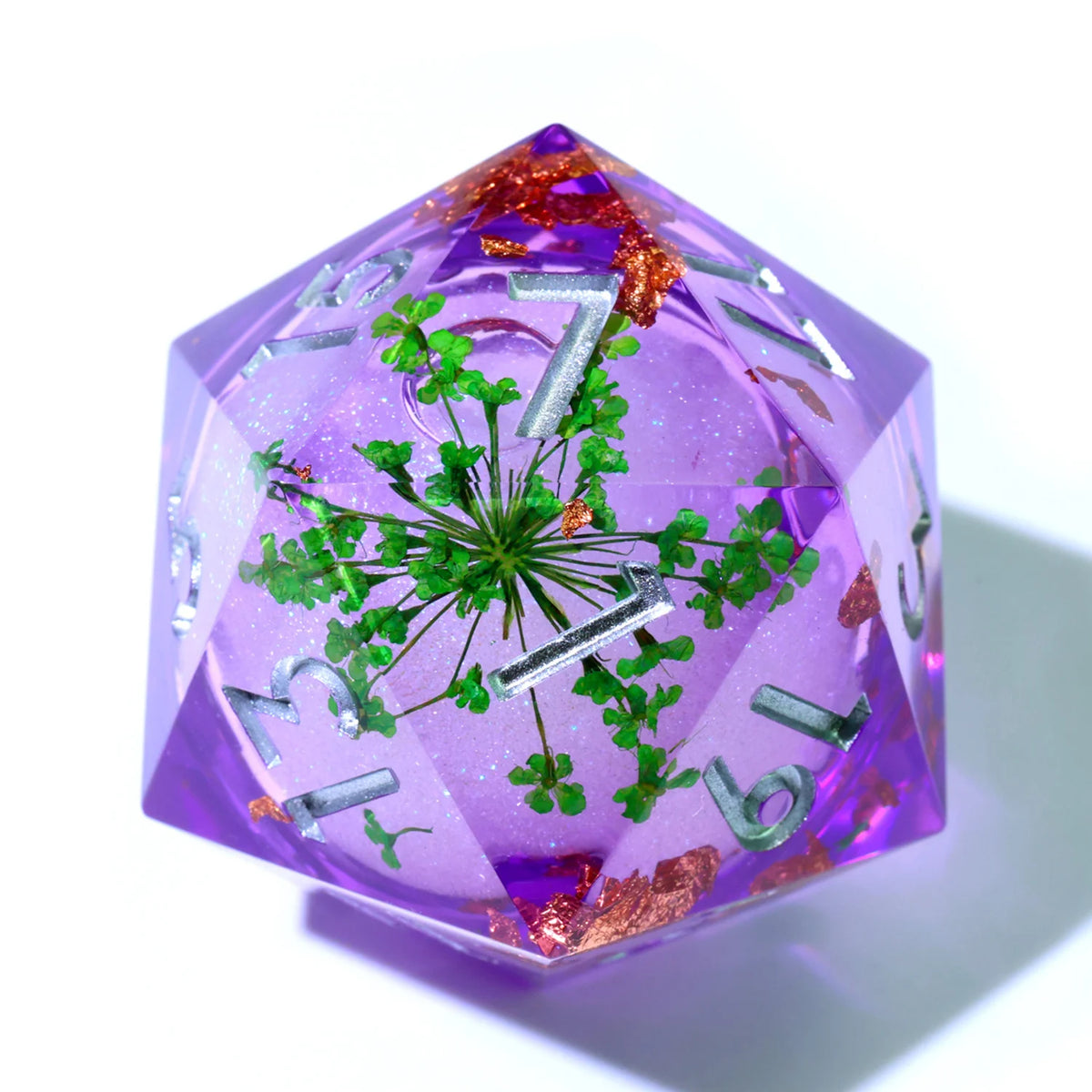 A faceted purple resin D20 die with a liquid swirl design featuring green foliage and gold accents.