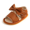 A pair of brown suede baby summer sandals with a bowknot and soft anti-slip sole.